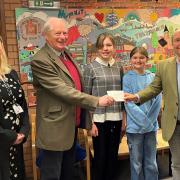 Philip Godsal, Chairman of Trustees of the Higher Wych School Charity, handing the cheque for £2,145 to Chair of Governors Steve Swinden, alongside Headteacher Emma Jones, and Year 6 school ambassadors Emily and Amelia.