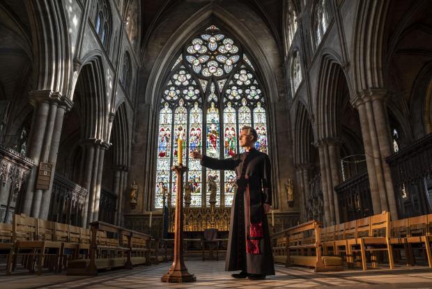 Whitchurch Herald: Very Reverend John Dobson Dean of Ripon lights a candle to mark the second anniversary of the first national coronavirus lockdown at Ripon Cathedral, North Yorkshire, ahead of the National Day of Reflection on Wednesday (PA)