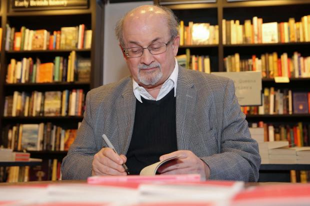 Salman Rushdie signs a book in a bookstore