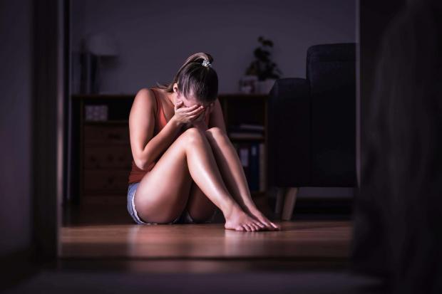 A young sad woman crying and sitting on the floor at home