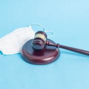 Judicial gavel and protective medical mask on a blue background.
